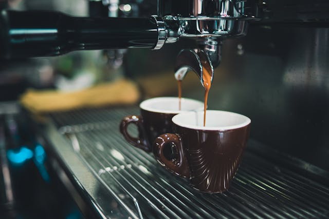 two shot of espresso being put into small brown mugs